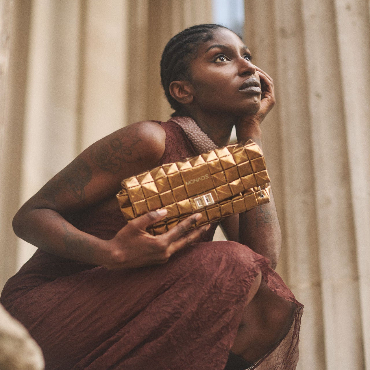 Woman holding a gold pouch bag  in an elegant outdoor setting