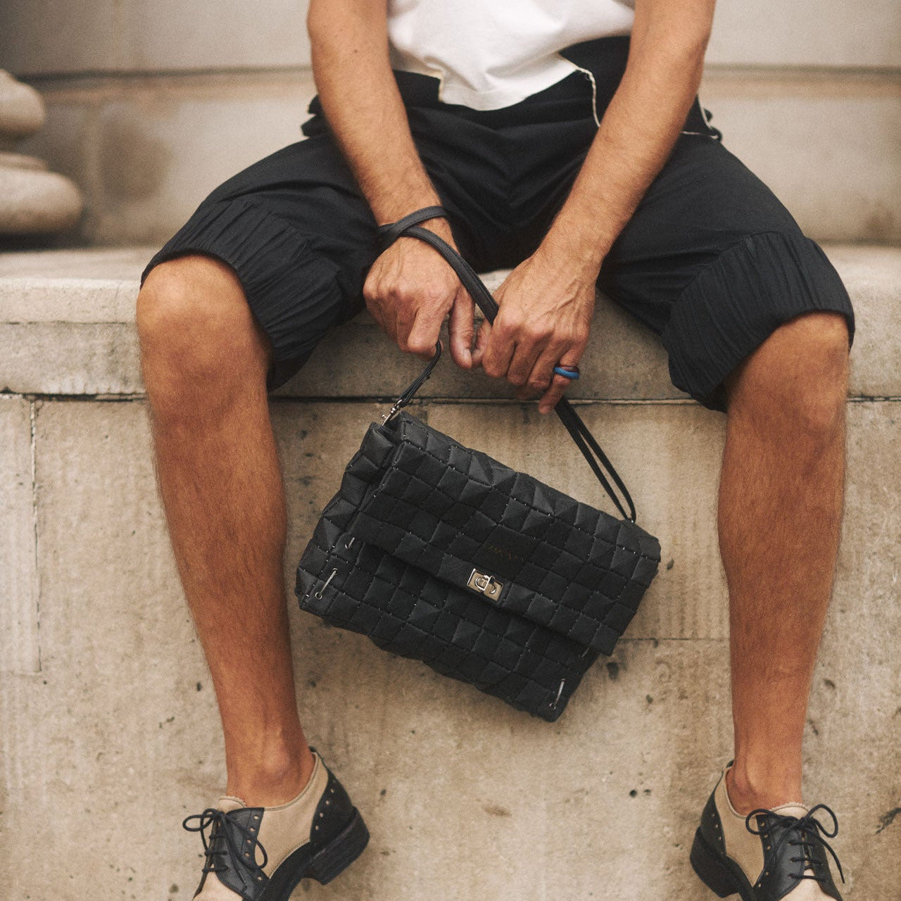 Person sitting on steps holding a black handbag